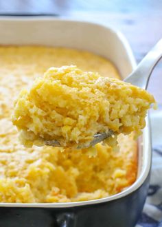 a spoonful of mashed potatoes is being lifted from a casserole dish