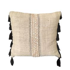 a black and white pillow with tassels on the front, sitting against a white background