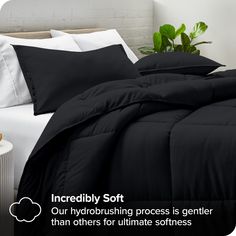 a bed with black sheets and white pillows on it, next to a potted plant