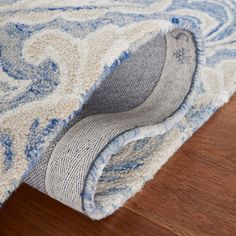 an area rug with a blue and white design on the bottom corner, laying on top of a wooden floor