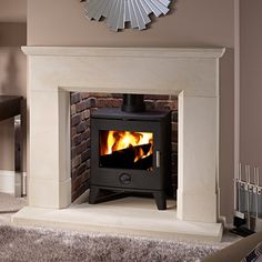 a wood burning stove in a living room next to a table and chair with a mirror on the wall