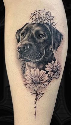 a black dog with flowers on his leg is shown in this tattoo design by person