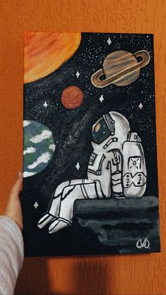 a drawing of an astronaut sitting on the moon with saturn in the sky behind him