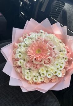 a bouquet of pink and white flowers in the back seat of a car