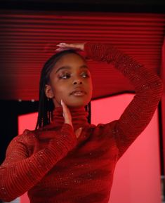 a woman in a red sweater is posing for the camera with her hand on her head