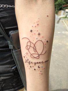 a woman with a tattoo on her arm that says life goes on and stars are in the sky