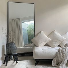 a white couch sitting in front of a large mirror