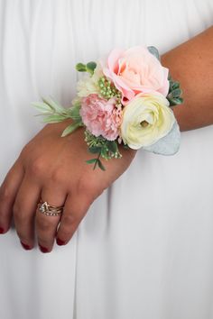 a woman wearing a white dress holding a bouquet of flowers on her arm with two wedding bands