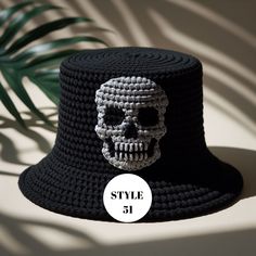 a crocheted hat with a skull on the front, and a palm leaf behind it