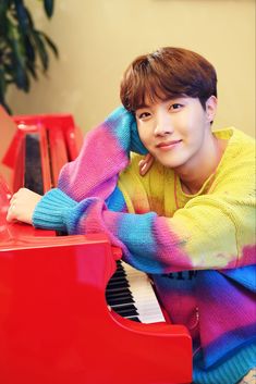 a young man sitting at a red piano