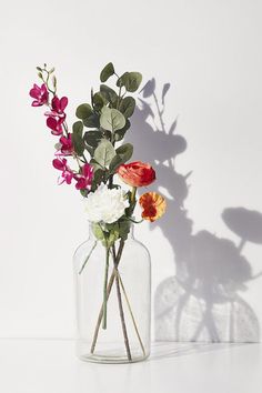 a vase filled with flowers sitting on top of a white table next to a wall