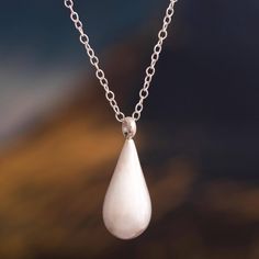 a white tear shaped pendant hangs from a chain