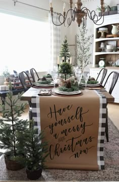 a dining room table decorated for christmas with greenery and pine cones on the table