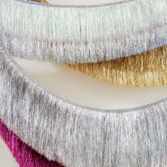 three metallic tinsel fringes on a white surface