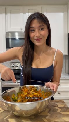 a woman in a blue tank top is holding a bowl of food