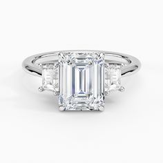 an emerald cut diamond ring with three baguets on the band and side stones