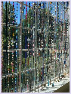 many necklaces are hanging on the side of a building in front of a window