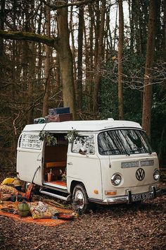 an old vw camper van is parked in the woods with its door open