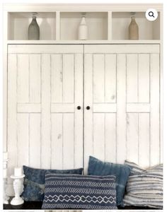 a white cabinet and some pillows on a table