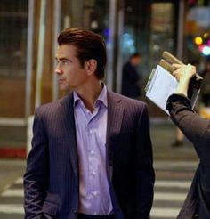 two men walking down the street talking to each other and one holding papers in his hand