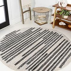 a round rug with black and white stripes on the floor next to a wooden shelf