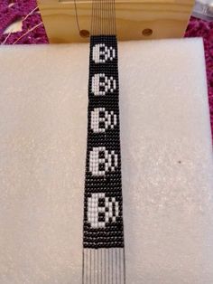 a beaded tie is sitting on top of a white box with the letters e, b, c, and d