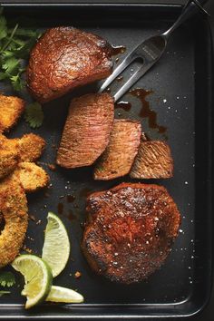 some meat and vegetables on a tray with a fork in the middle next to it