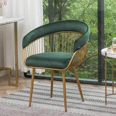 a green chair sitting in front of a window next to a table with a vase on it