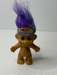 a toy troll with purple hair on it's head