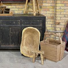 an old wooden chair sitting next to a piece of wood and other items in front of a brick wall