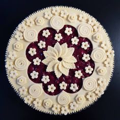 a pie with white and red toppings on black table top, ready to be eaten