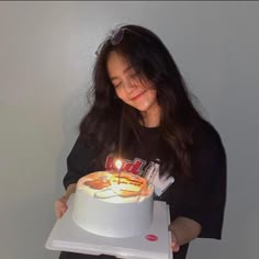 a woman holding a birthday cake with lit candles