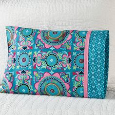 a blue and pink pillow sitting on top of a bed