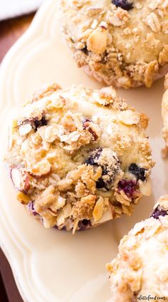 blueberry muffins on a white plate with crumbs and oats