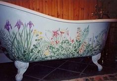 an old bathtub painted with flowers and plants on the side, in a bathroom