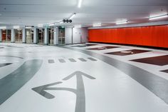 an empty parking garage with red doors and white flooring that has arrows painted on it