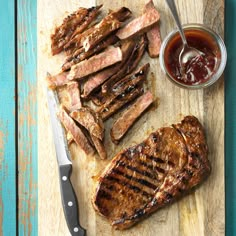 grilled steak and french fries on a wooden cutting board with ketchup sauce