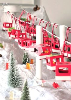 there are many red and white toy trains on the train track with christmas trees around them