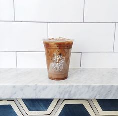 a drink sitting on top of a marble counter next to a white tile backsplash