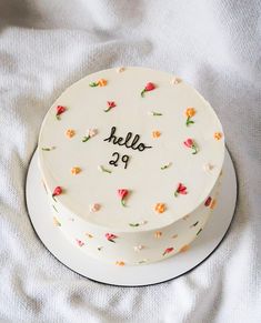 a white cake with flowers on it sitting on top of a cloth covered tablecloth