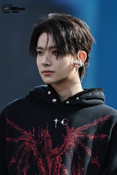 a young man with black hair and piercings on his ear wearing a hoodie