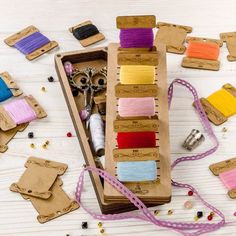 an open box filled with lots of different colored thread and spools on top of a table