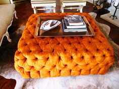 an orange tufted ottoman in the middle of a living room