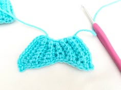 the crochet bow is being worked on with a pink knitting needle next to it