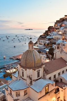 an aerial view of a city by the ocean at dusk with boats in the water