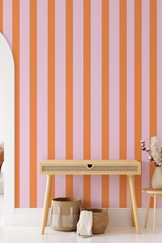 an orange and pink striped wallpaper in a living room with two chairs, a table and vases