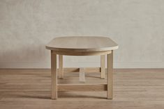 a wooden table sitting on top of a hard wood floor next to a white wall