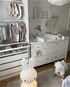 a baby's room with white furniture and lots of clothes on the shelves in it