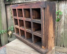 an old wooden shelf with many compartments on it and ivy growing up the side of it