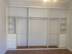 an empty room with white closets and drawers